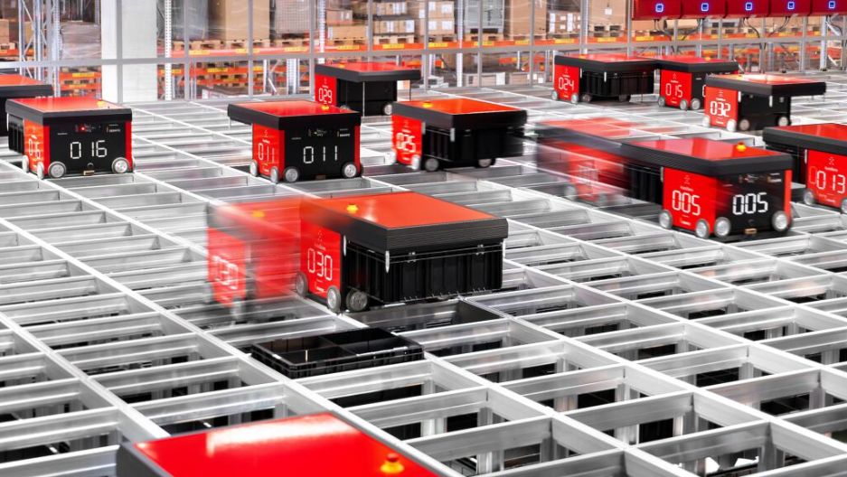 Rote Roboter bewegen sich auf einem Gitter in einem Lager.