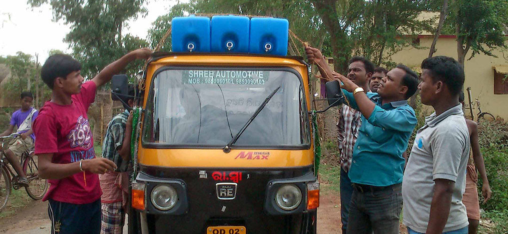 Mehrere Männer befestigen blaue Kanister auf einem Auto.