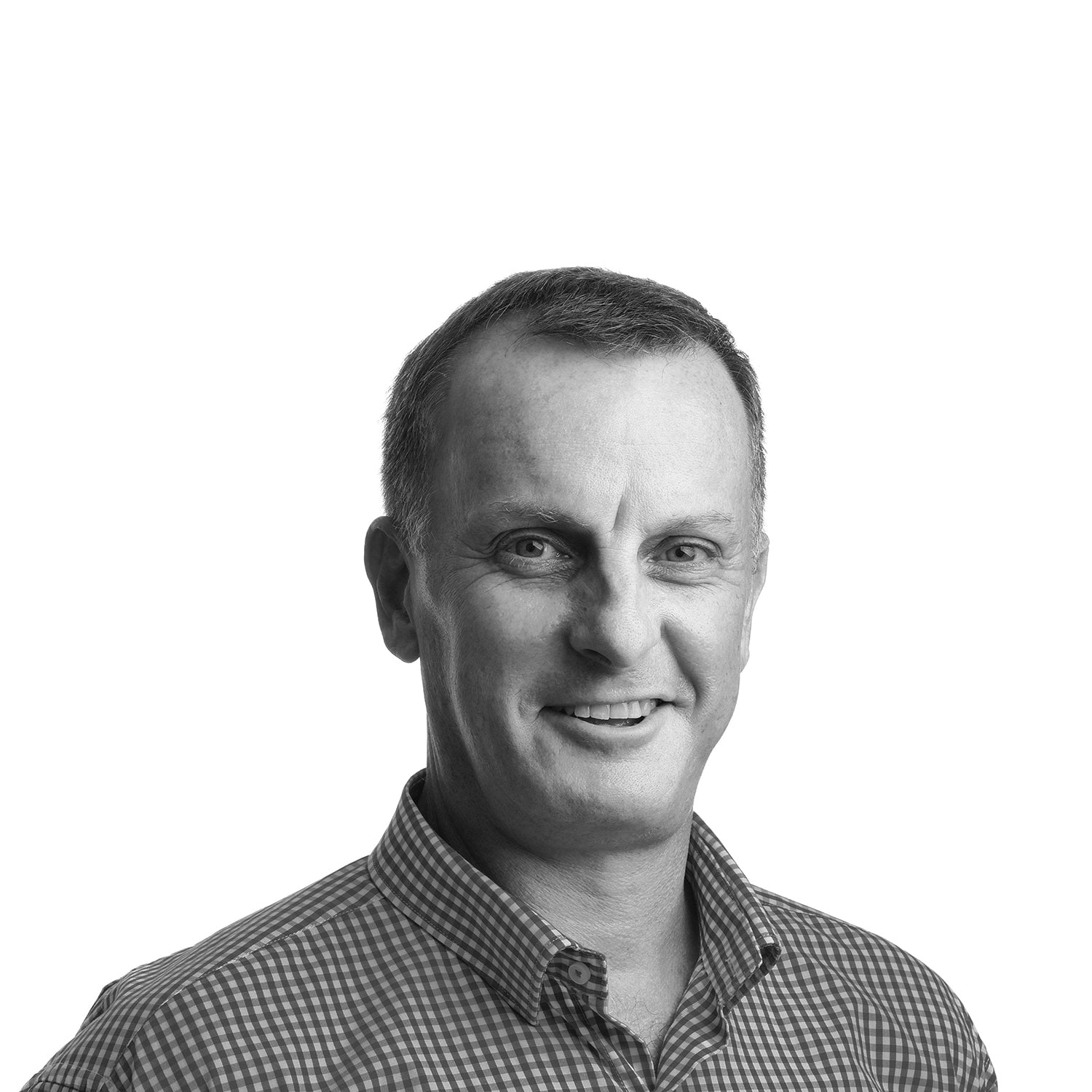 Mann in kariertem Hemd lächelt vor neutralem Hintergrund.